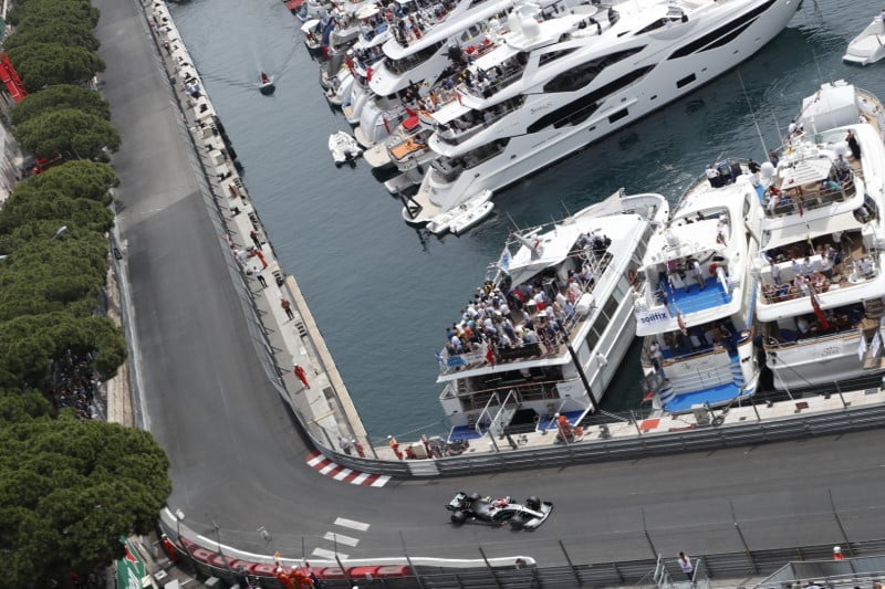 A Mercedes F1 car races through the streets of Monaco during the history Monaco Grand Prix.
